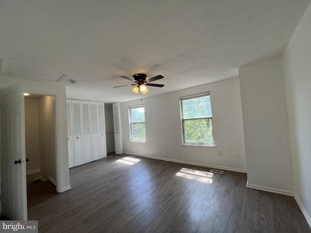 unfurnished bedroom with a ceiling fan, baseboards, dark wood-type flooring, visible vents, and a closet