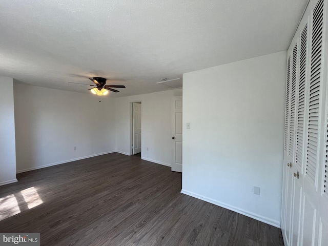 unfurnished bedroom with baseboards, ceiling fan, dark wood-style floors, and a closet