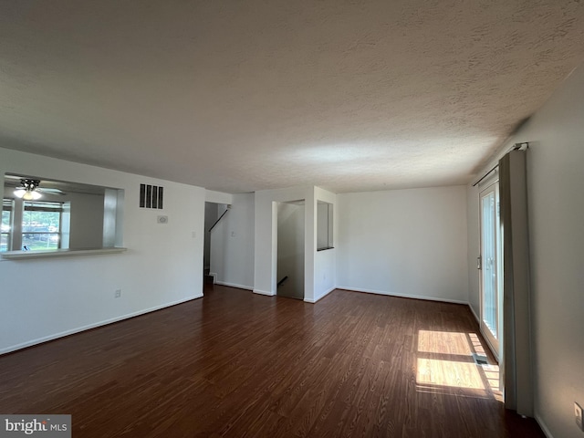 unfurnished room featuring baseboards, a ceiling fan, dark wood-style floors, and visible vents