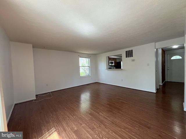 unfurnished living room with baseboards, wood finished floors, and visible vents