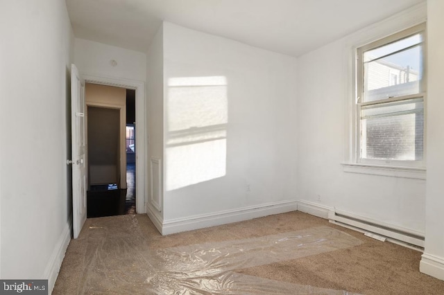 spare room with baseboards, a baseboard heating unit, and carpet