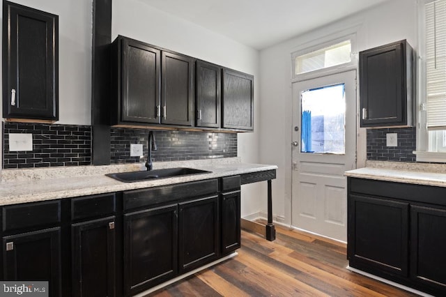 kitchen featuring dark wood-style flooring, dark cabinets, a sink, and tasteful backsplash