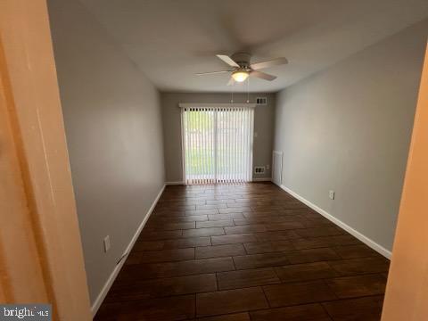 unfurnished room with baseboards, dark wood-style flooring, and ceiling fan
