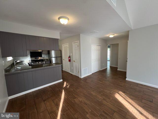 kitchen featuring dark wood-type flooring, freestanding refrigerator, a peninsula, and open floor plan