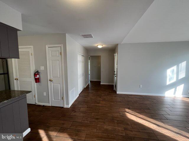 interior space featuring visible vents, baseboards, and dark wood-type flooring