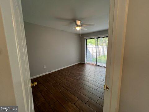 spare room featuring dark wood-style flooring, ceiling fan, and baseboards