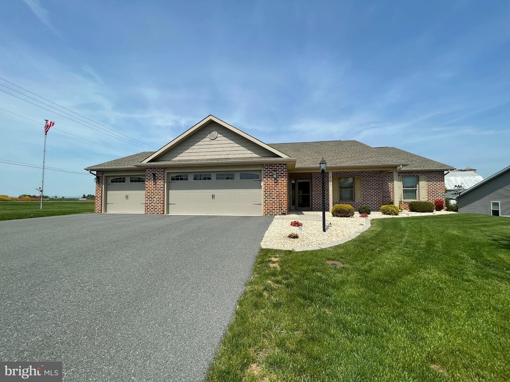 view of front of property featuring a garage, driveway, brick siding, and a front yard