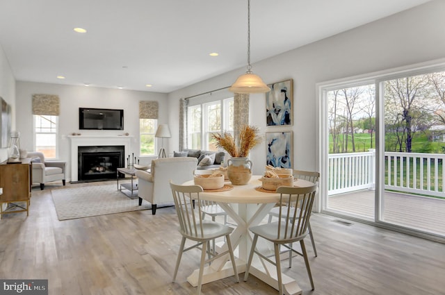 dining room featuring light wood-type flooring, a fireplace with flush hearth, visible vents, and recessed lighting