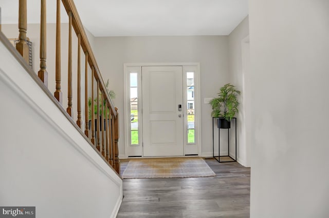 entryway with stairs, baseboards, and wood finished floors