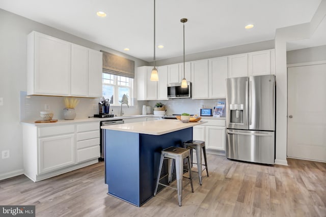 kitchen with decorative backsplash, a breakfast bar, a center island, white cabinetry, and appliances with stainless steel finishes