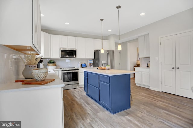 kitchen featuring backsplash, blue cabinets, appliances with stainless steel finishes, light wood-type flooring, and white cabinetry