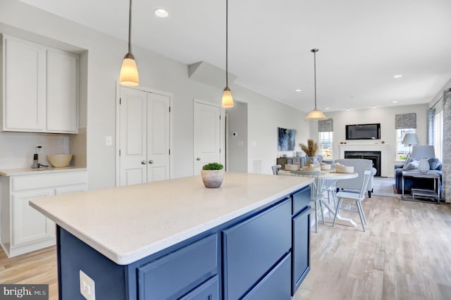 kitchen featuring light countertops, white cabinets, blue cabinets, light wood finished floors, and hanging light fixtures