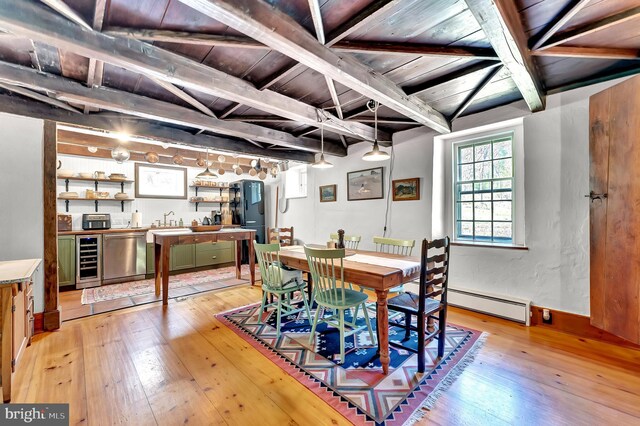 dining space with light wood-style floors, beam ceiling, a baseboard heating unit, and beverage cooler