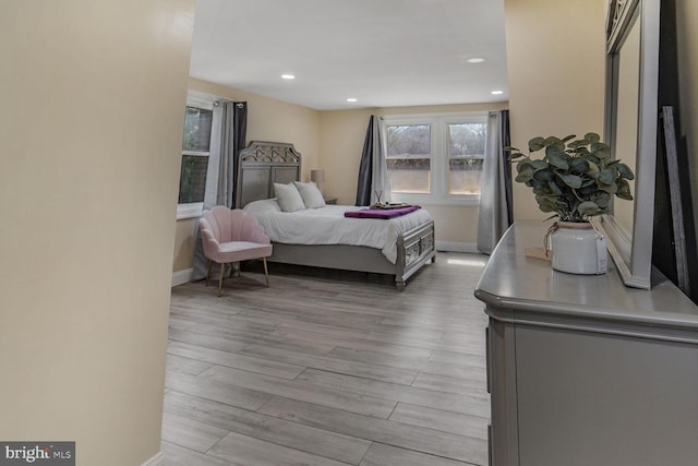 bedroom with baseboards, recessed lighting, and light wood-style flooring