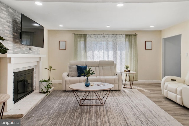 living room featuring baseboards, recessed lighting, a glass covered fireplace, and wood finished floors