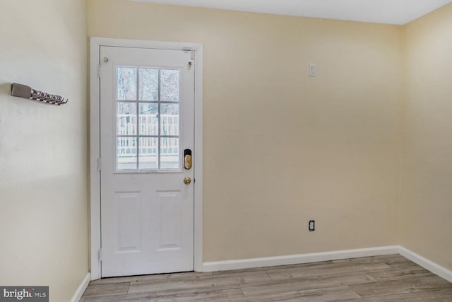 doorway to outside featuring baseboards and light wood finished floors