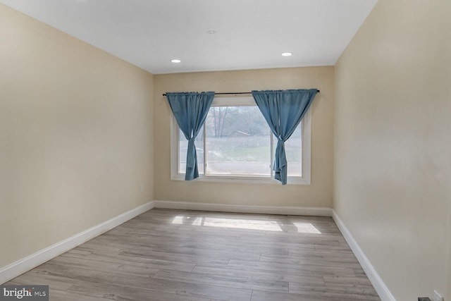 spare room featuring baseboards, recessed lighting, and wood finished floors