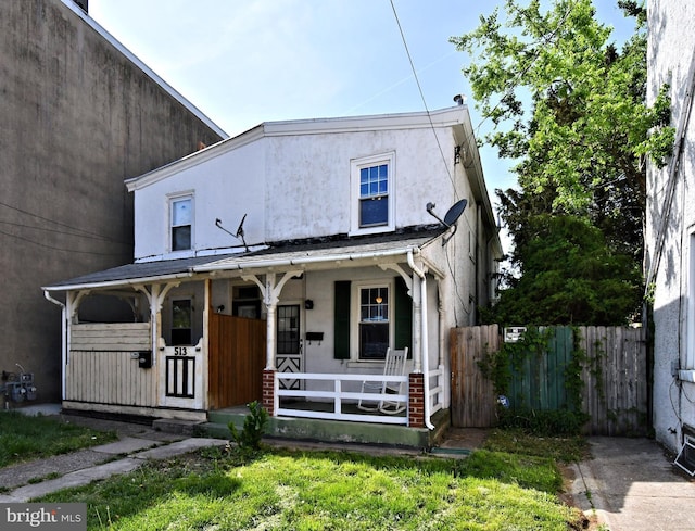 view of front facade featuring stucco siding, fence, and covered porch