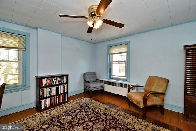 sitting room with wood-type flooring, a ceiling fan, baseboards, and radiator heating unit