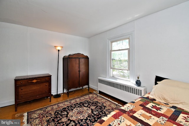 bedroom featuring wood finished floors, baseboards, and radiator heating unit