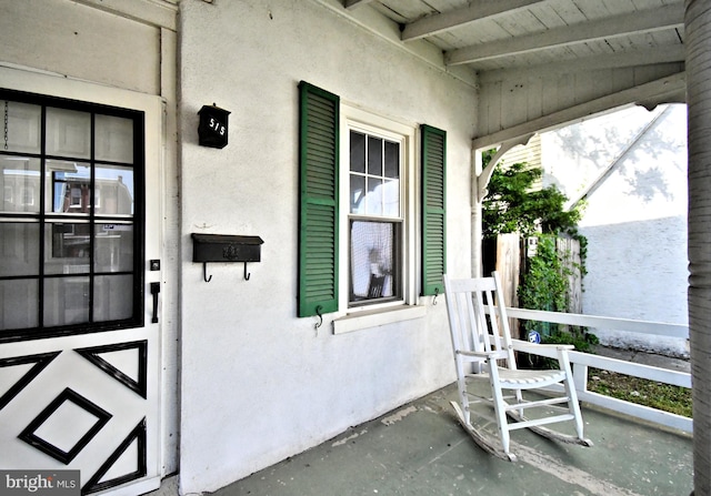 entrance to property featuring covered porch and stucco siding