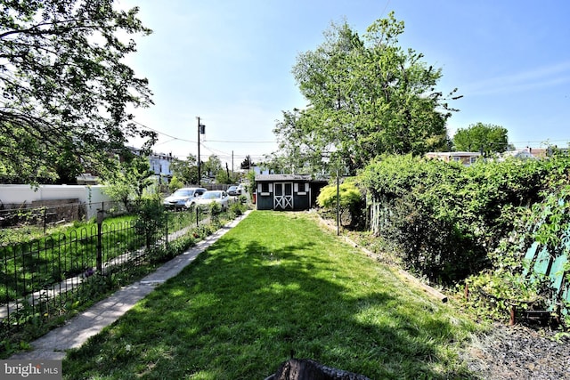 view of yard with fence, an outbuilding, and a shed