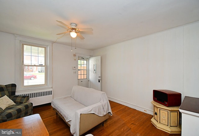 living room featuring radiator, baseboards, a ceiling fan, and wood finished floors