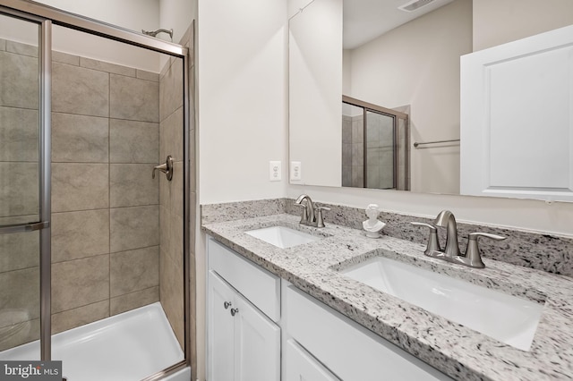 full bath with double vanity, visible vents, a sink, and a stall shower