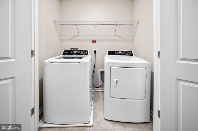 clothes washing area with laundry area, light tile patterned floors, and washing machine and dryer