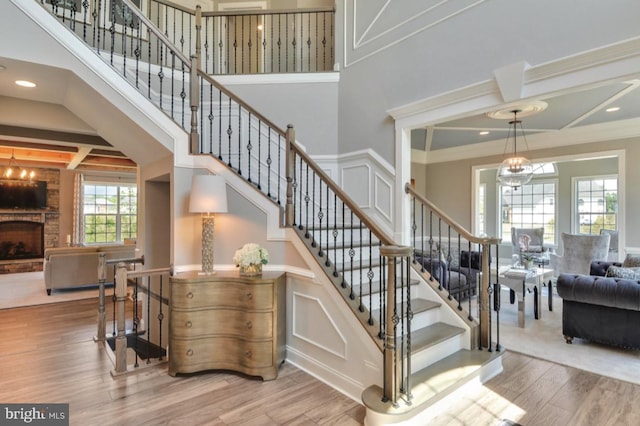 17905 Queen Anne Rd, Upper Marlboro, MD 20774 - staircase featuring an inviting chandelier, a towering ceiling, wood finished floors, beam ceiling, and a fireplace with raised hearth