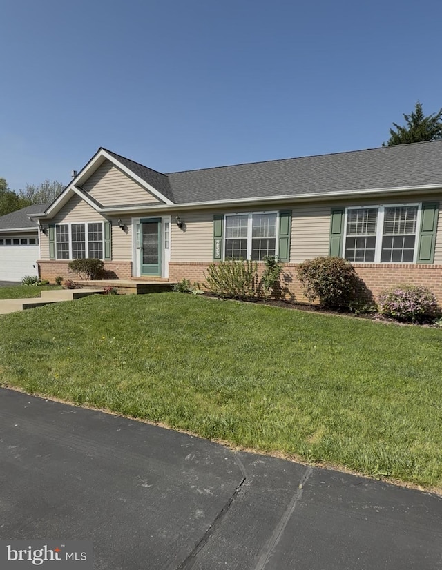 ranch-style house featuring a shingled roof, a front yard, and brick siding