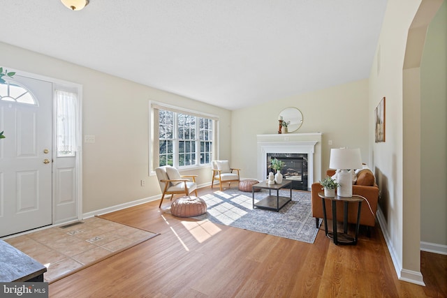 living room with baseboards, wood finished floors, visible vents, and a fireplace