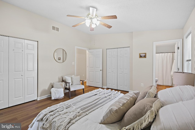 bedroom featuring connected bathroom, two closets, wood finished floors, and visible vents