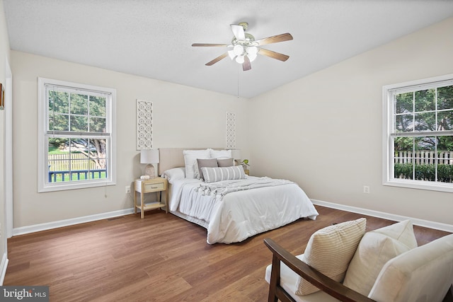 bedroom with baseboards, ceiling fan, wood finished floors, and visible vents