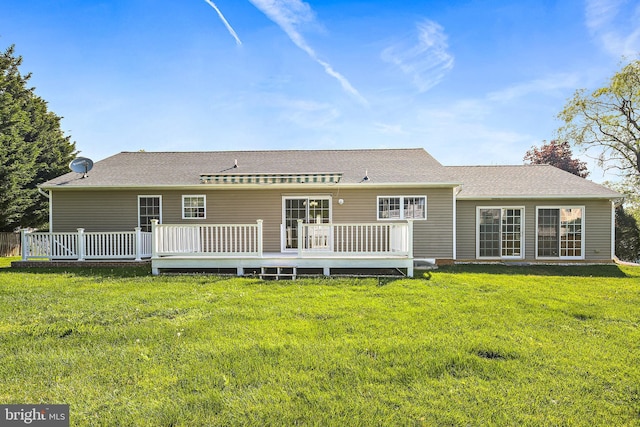 rear view of house featuring a lawn, a wooden deck, and a shingled roof