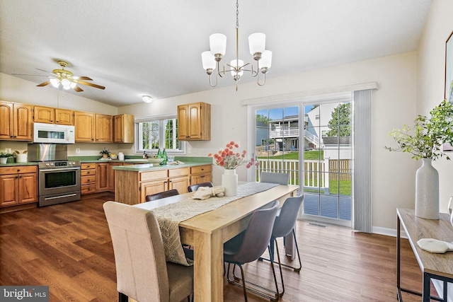 dining room featuring dark wood-style flooring, visible vents, ceiling fan with notable chandelier, baseboards, and vaulted ceiling