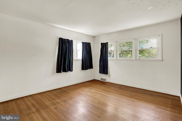 empty room featuring visible vents, light wood finished floors, and baseboards