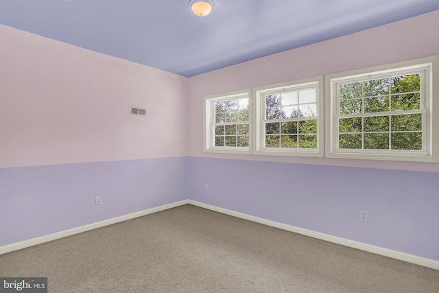 empty room featuring carpet flooring, baseboards, and visible vents