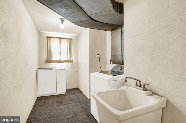 laundry room with a textured wall, laundry area, a sink, carpet, and washer / clothes dryer