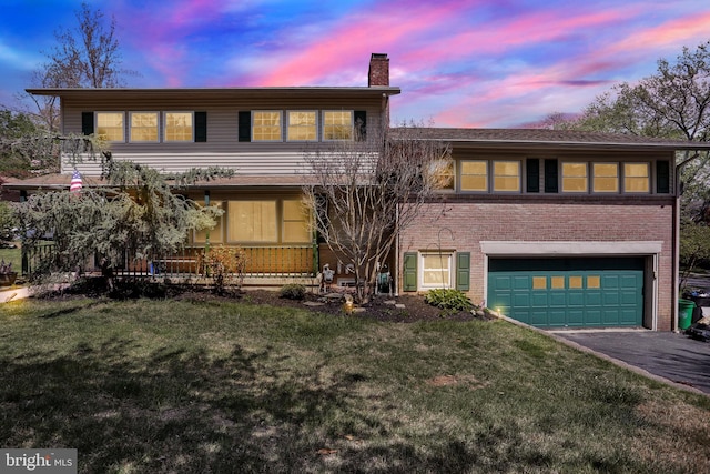 view of front facade with a garage, a front lawn, a chimney, brick siding, and driveway