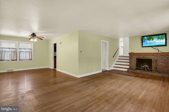 unfurnished living room featuring stairs, visible vents, hardwood / wood-style floors, and a fireplace
