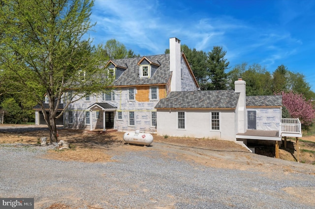 view of front of home with stucco siding, stone siding, a chimney, and a deck