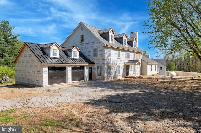 view of home's exterior with a standing seam roof, a chimney, driveway, and metal roof