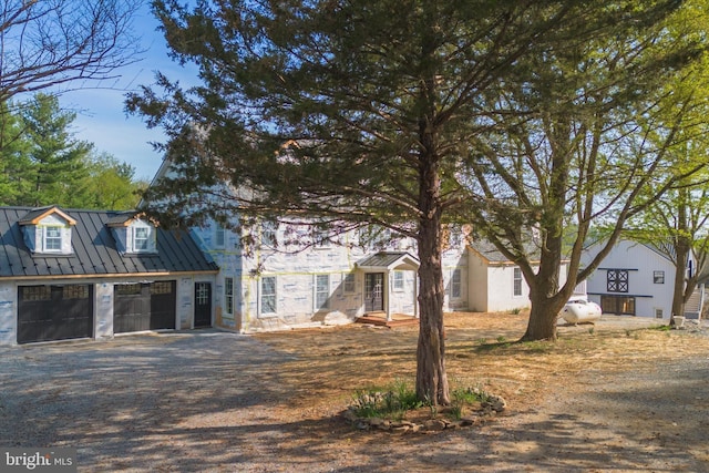 view of front facade with metal roof, a garage, driveway, and a standing seam roof