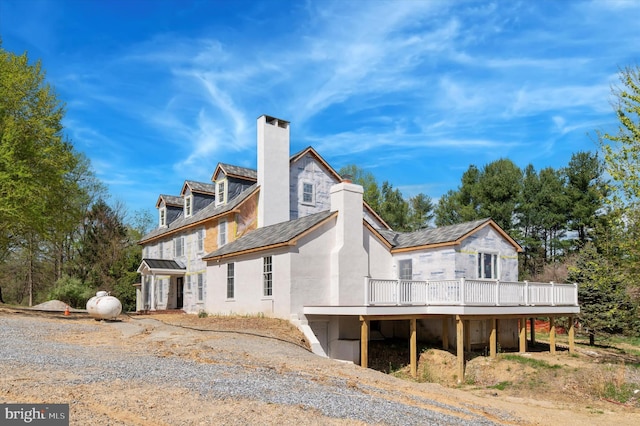 view of side of property featuring a chimney, stucco siding, and a deck