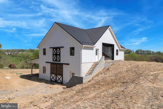 exterior space featuring a standing seam roof, an outbuilding, stairs, and metal roof