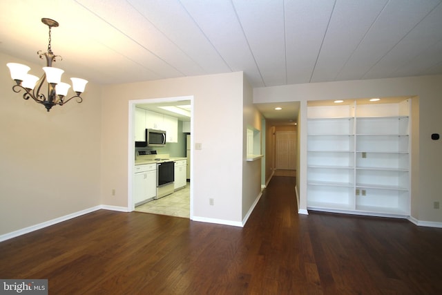 unfurnished dining area featuring baseboards, an inviting chandelier, built in features, and wood finished floors