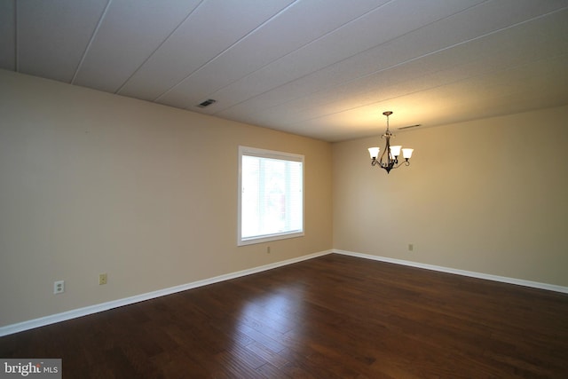 unfurnished room with an inviting chandelier, baseboards, dark wood-style flooring, and visible vents