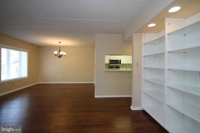 interior space featuring baseboards, a notable chandelier, and dark wood-type flooring