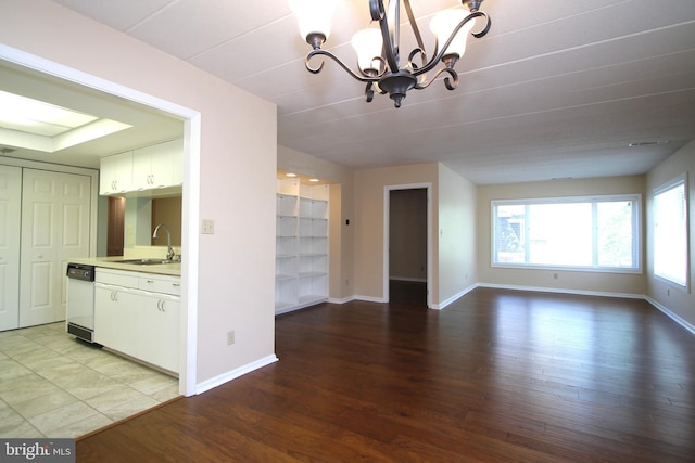 unfurnished dining area featuring baseboards, a notable chandelier, a sink, and wood finished floors